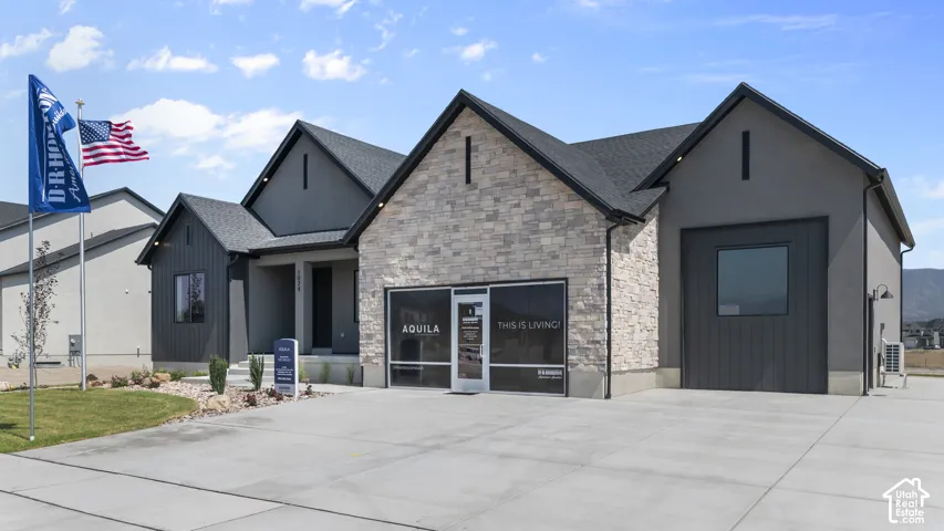 Contemporary exterior featuring stone accents, dark-toned siding, and a black shingle roof