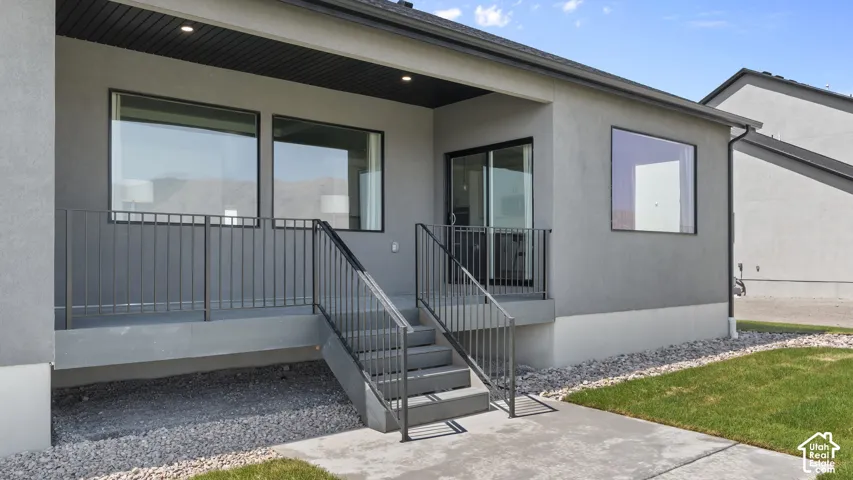 Rear patio with dark gray stucco exterior, black-framed windows, and a black metal railing
