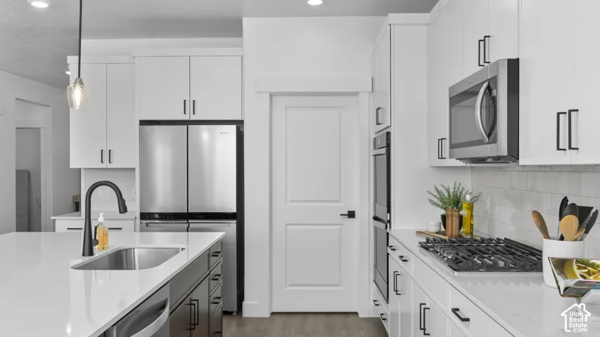 White cabinetry with matte black hardware, stainless steel appliances, built-in wall oven, gas cooktop, and an undermount sink