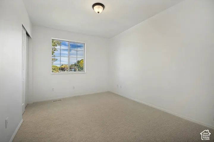 Neutral wall tones, carpeted flooring, a window with grid panes, and a flush-mount ceiling light