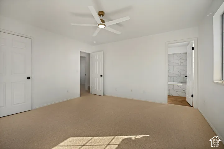 Neutral-toned carpeting, white interior doors, and a ceiling fan with integrated lighting