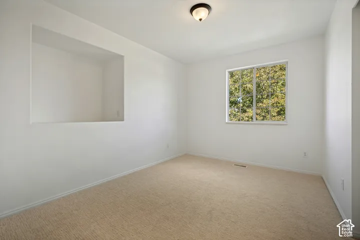 Recessed wall niche, broad window, neutral carpeting, and a flush mount light fixture