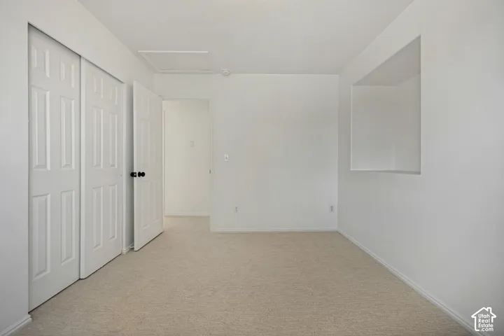 Neutral toned carpeting, built-in shelving, paneled doors, and a ceiling access panel