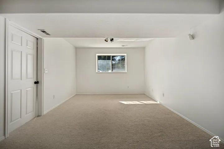 Carpeted room with a double-pane window, white walls, and a paneled door