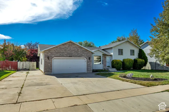 Brick and siding exterior with a two-car garage, concrete driveway, and established landscaping