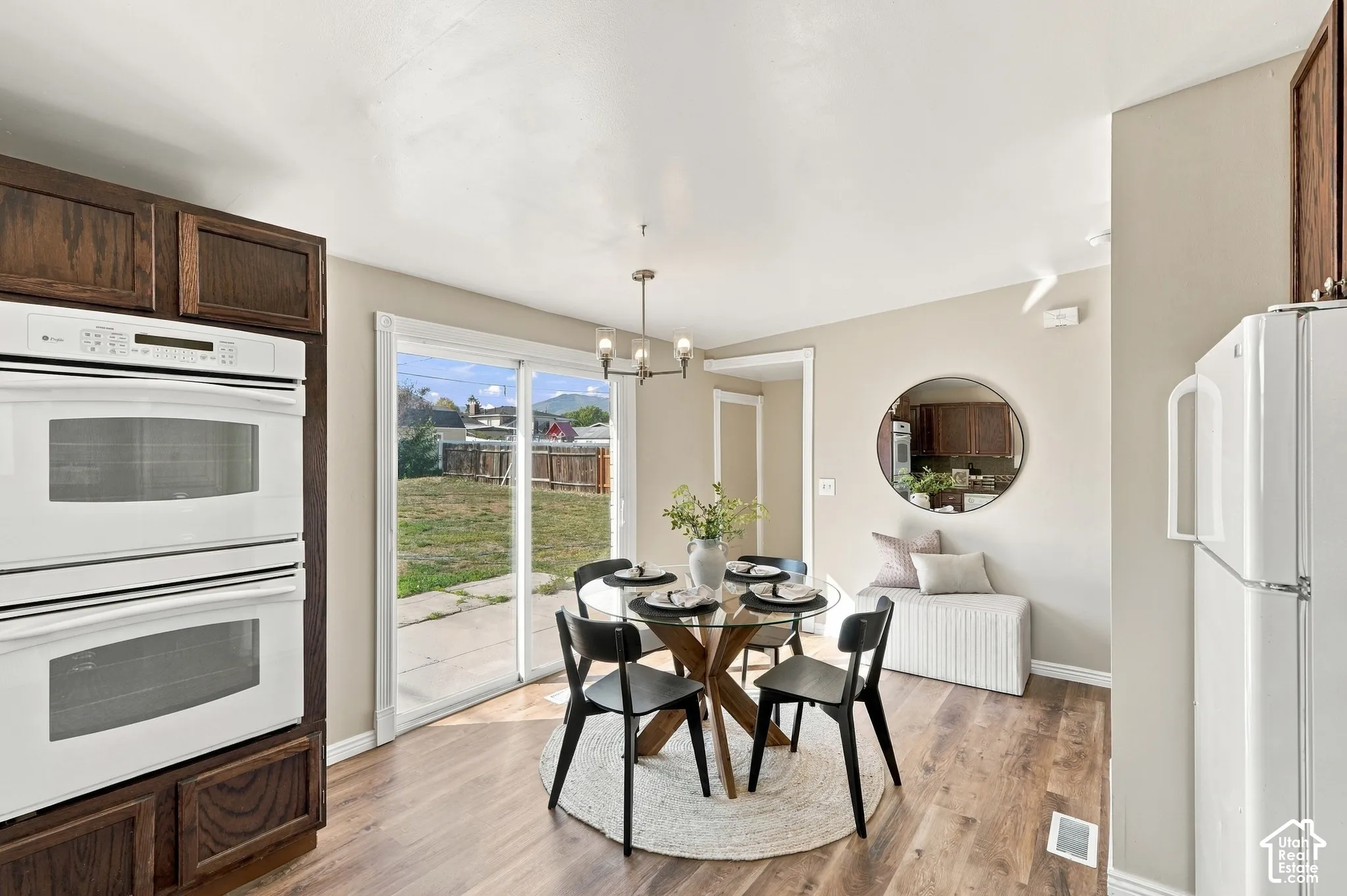 Built-in double ovens, wood-finish flooring, sliding glass door, modern chandelier, and dark wood cabinetry