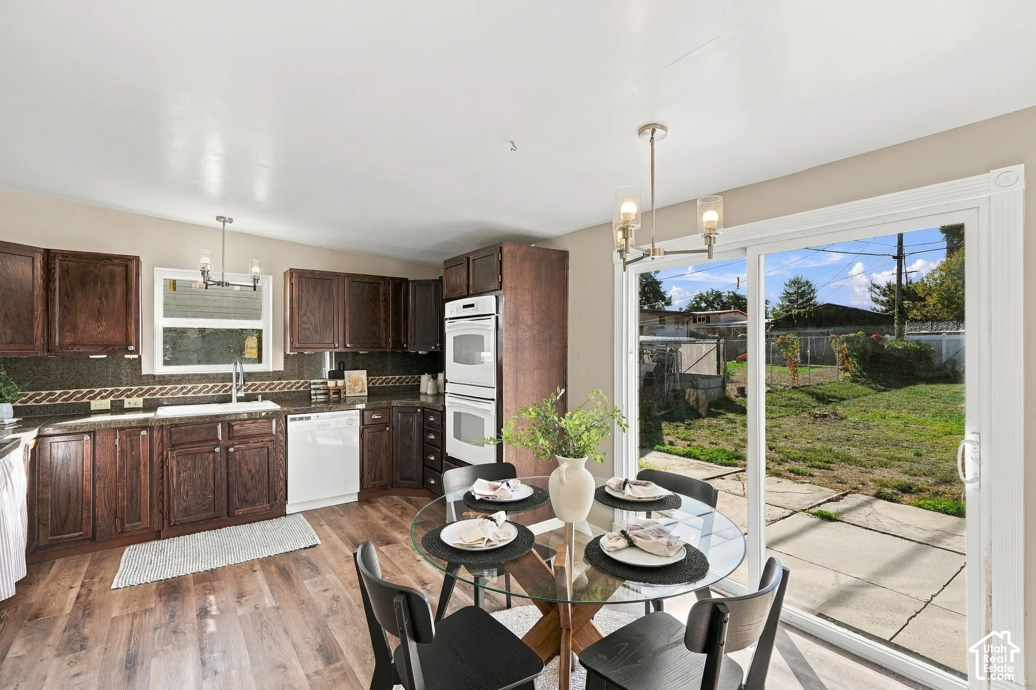 Wood-finish flooring throughout, dark wood cabinetry, and a dark tile backsplash
