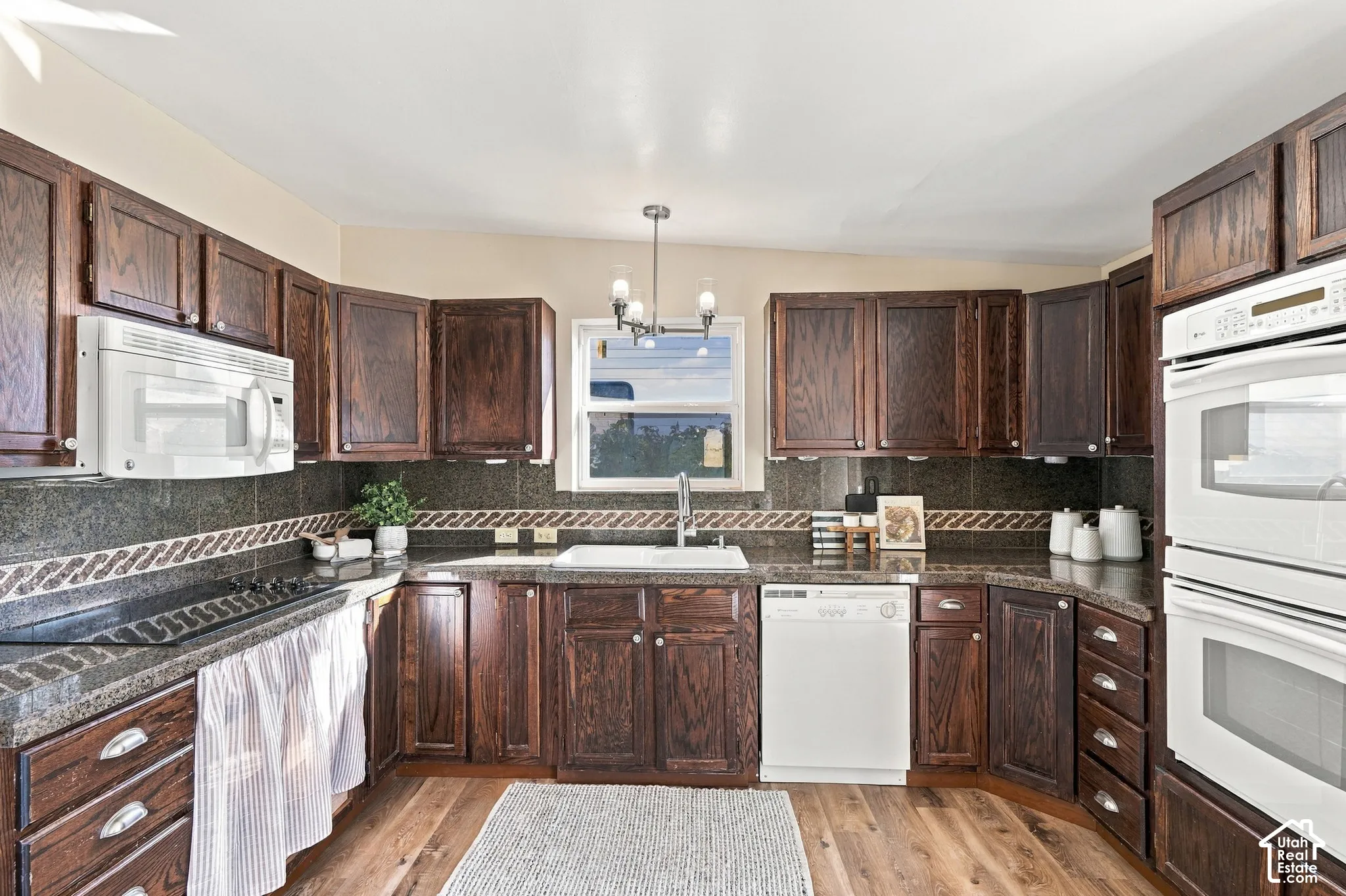 Wood-finish flooring with dark wood cabinetry, a built-in double oven, and a built-in microwave