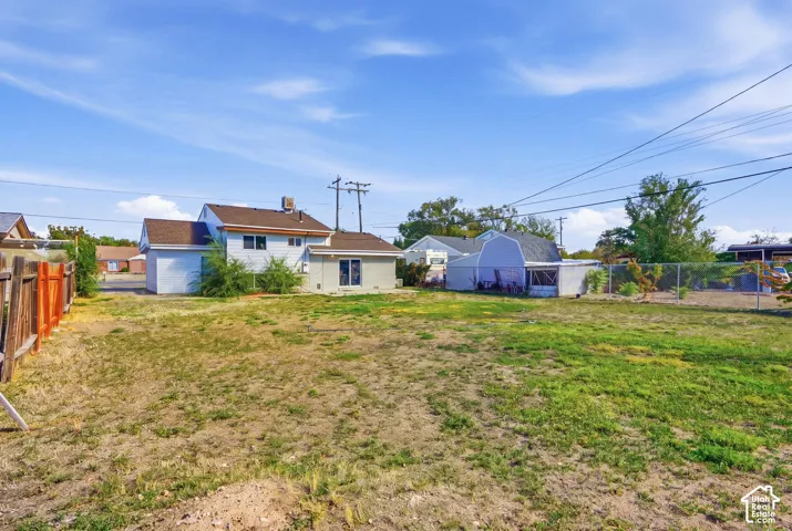 Expansive outdoor space featuring a partial wood fence, partial chain-link fence, and a detached shed