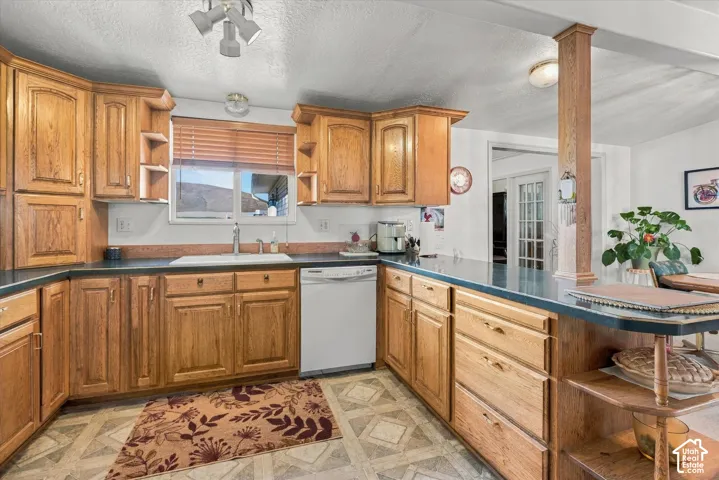 Spacious kitchen featuring warm wood cabinetry, stainless steel appliances, blue-toned countertops, a central island with storage, and abundant natural light from multiple windows