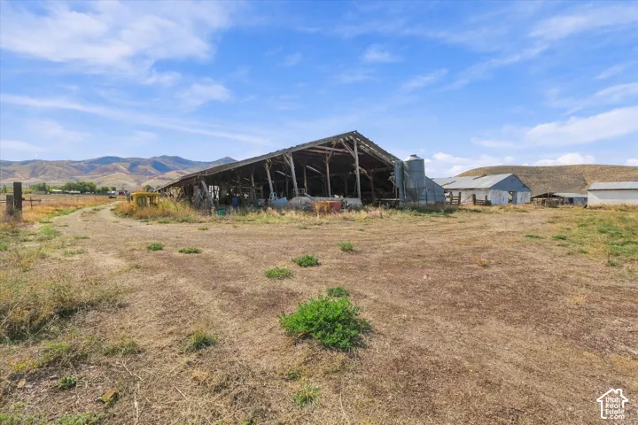 Expansive rural property featuring an agricultural building, a metal silo, and additional structures, set against a mountainous backdrop