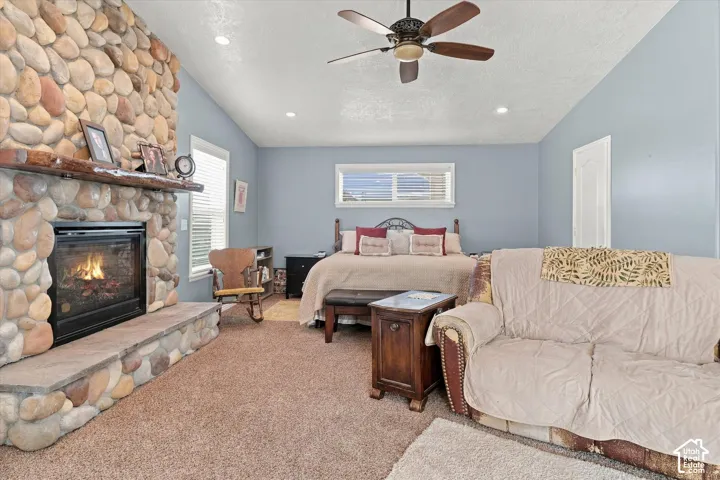 Stone-faced fireplace with a wood mantel, vaulted ceiling, recessed lighting, and a ceiling fan
