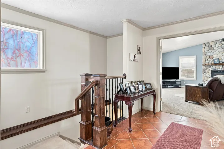 Entryway with terracotta-style tile flooring, wood-finish staircase newel posts, and a decorative window