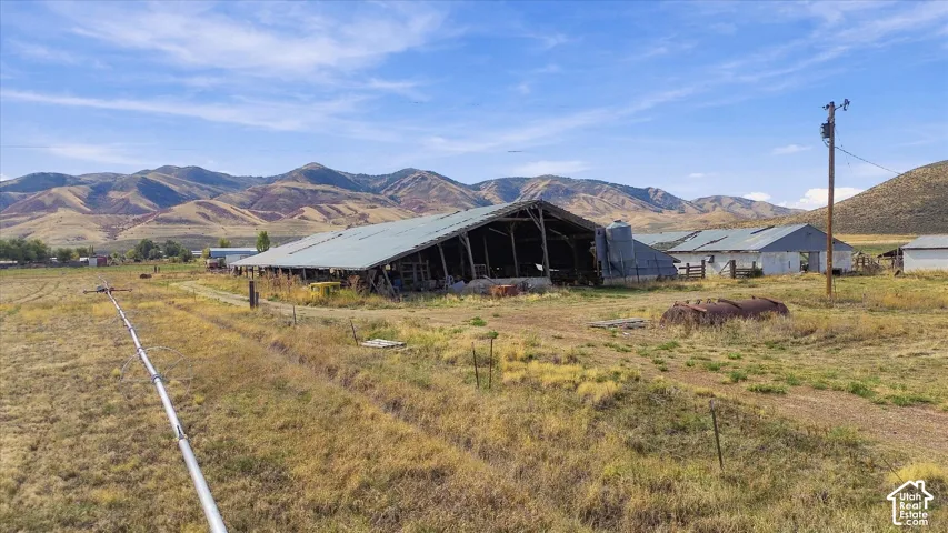 Expansive rural property featuring multiple agricultural structures, a large metal-roofed barn, and a substantial open field area