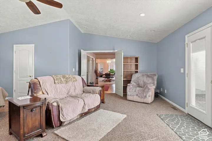 Vaulted ceiling with a ceiling fan, light blue walls, and carpet flooring