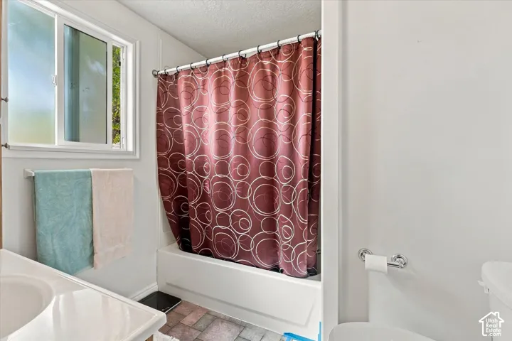 Tub and shower combination with a single-pane window, white vanity with integrated sink, and tile flooring