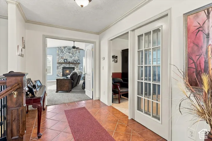 Tiled entryway with crown molding and wood railing