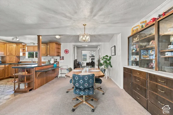 Dining area with carpet flooring, an ornate chandelier, and a built-in display cabinet with glass doors