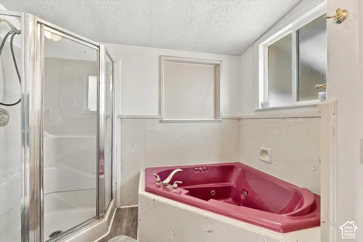 Shower enclosure with a glass door, corner soaking tub, and frosted window