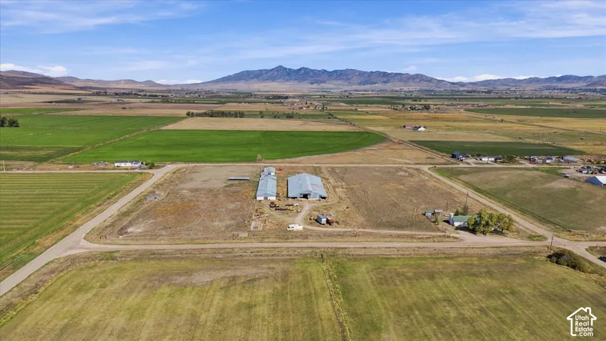 Expansive rural property featuring multiple agricultural buildings, cultivated fields, and mountainous scenery