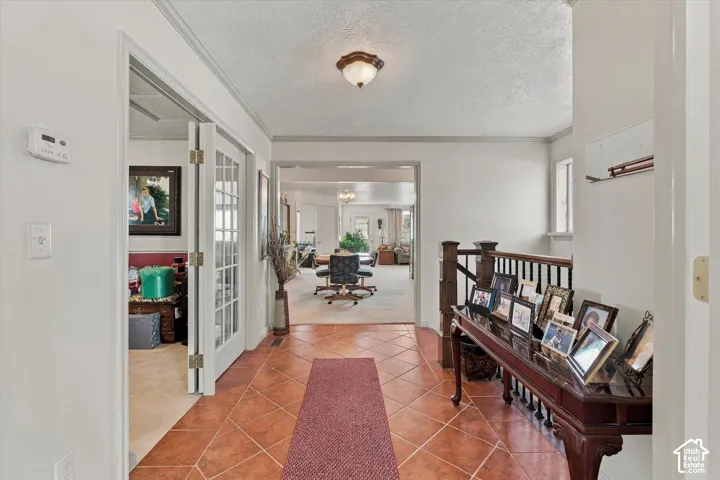 Foyer featuring terracotta-style tile flooring, French doors, and a wood-finish staircase railing