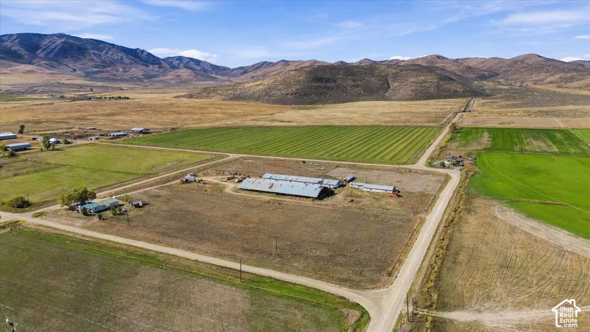Expansive rural property featuring multiple agricultural structures, cultivated fields, and unpaved roads