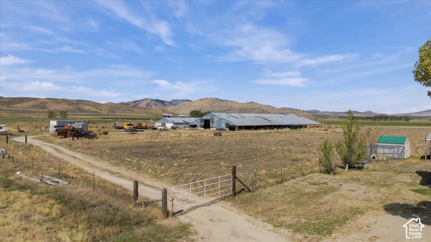 Expansive property featuring multiple outbuildings, agricultural fields, and mountainous terrain