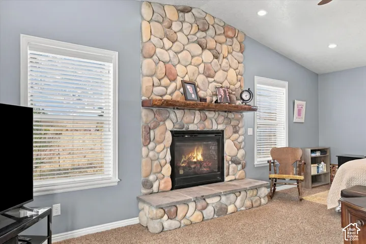 Spacious living area featuring a striking stone fireplace with gas insert, wooden mantel, and built-in shelving