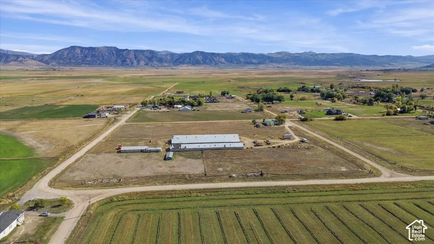 Expansive property featuring multiple outbuildings, agricultural fields, and a prominent mountain range backdrop