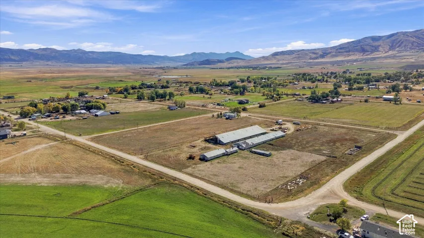Expansive rural setting with multiple outbuildings, agricultural fields, and distant mountain ranges