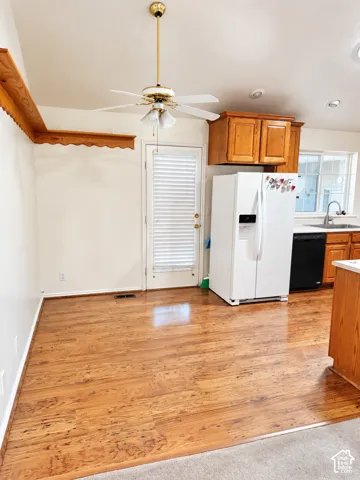 Wood-finish flooring, ceiling fan with integrated lighting, recessed lighting, wood cabinetry, and a white paneled door with integrated blinds
