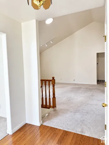 Vaulted ceiling, wood-finish flooring, recessed lighting, track lighting, and a wood railing