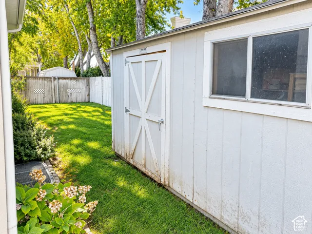 White-painted shed with a paneled exterior and a side-mounted window