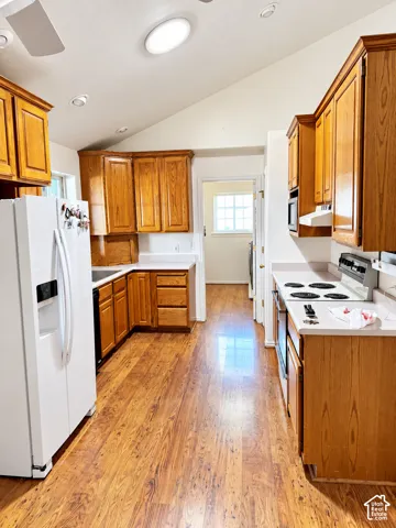 Kitchen featuring wood-finish flooring, vaulted ceilings, recessed lighting, wood cabinetry, and white countertops