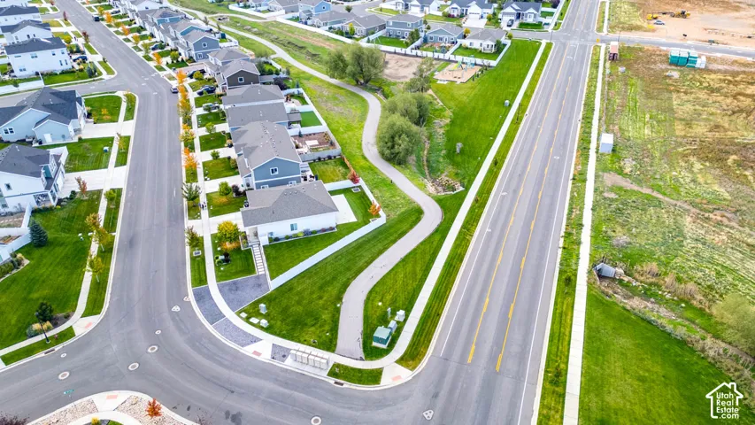 Modern residential development featuring a paved street, extensive green spaces, and a winding pedestrian path