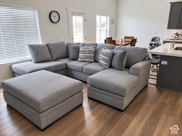 Open-concept living space featuring wood-finish flooring, white walls, and a window with blinds