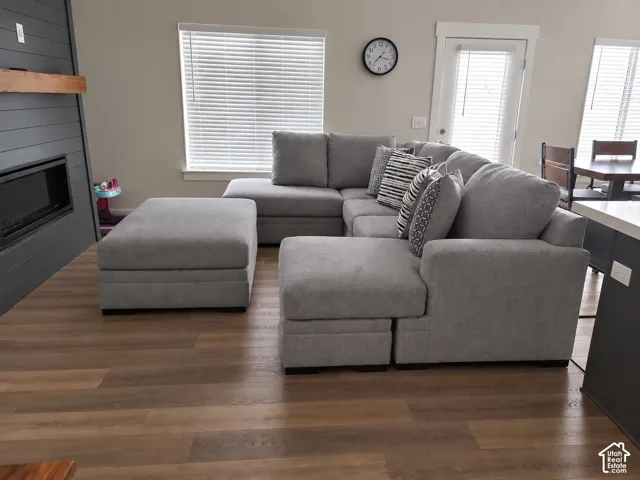 Modern living area featuring wood-finish flooring, a contemporary fireplace with a dark shiplap surround, and a light wood mantel