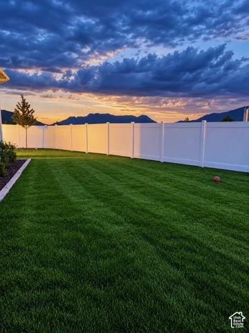 Expansive lawn with manicured grass, white privacy fencing, and a distinct planting bed