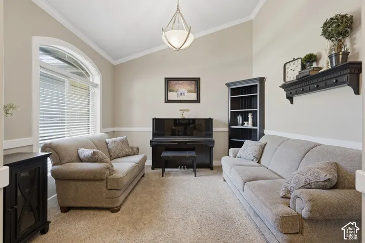 Vaulted ceilings with crown molding, arched window, two-tone wall treatment, and carpeted flooring