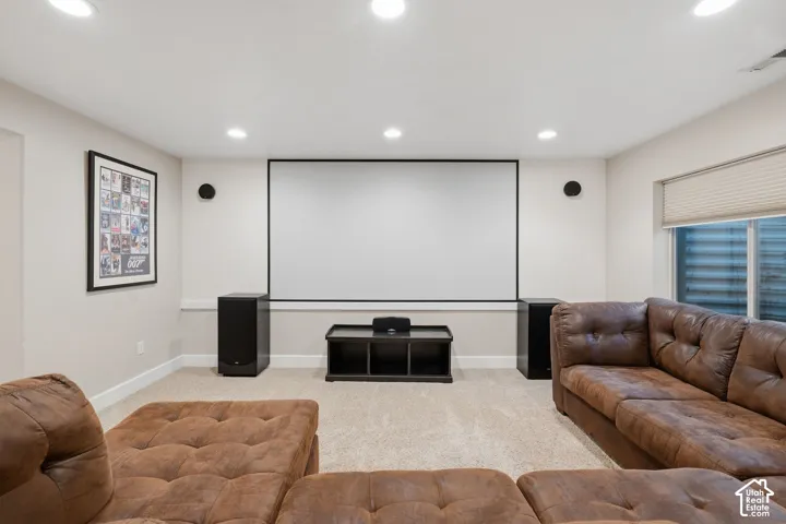 Dedicated media room featuring a large projector screen, recessed lighting, and neutral wall tones