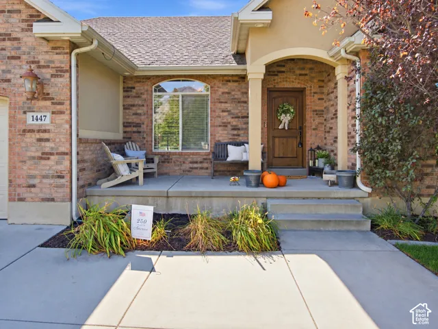 Brick facade with a covered porch featuring an arched entryway, prominent columns, and a solid wood front door