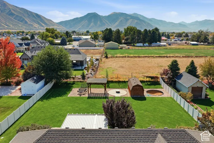 Expansive backyard with a manicured lawn, white vinyl fencing, a detached shed, and a dedicated patio area with a gazebo