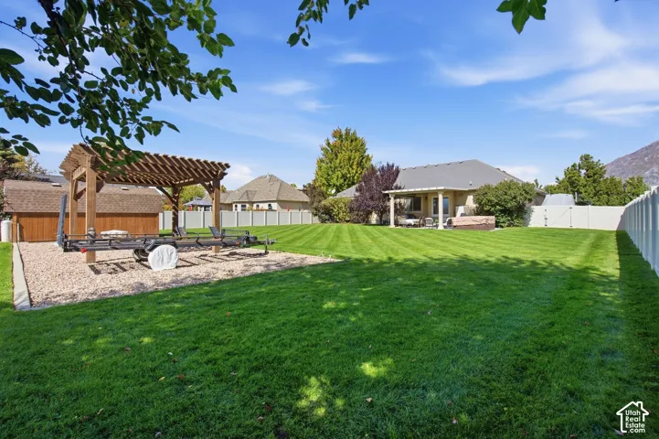 Expansive lawn area with a gravel pad and wooden pergola