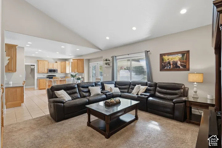 Vaulted ceiling with recessed lighting, carpeting, and a kitchen featuring wood-finish cabinetry, built-in microwave, and tile flooring