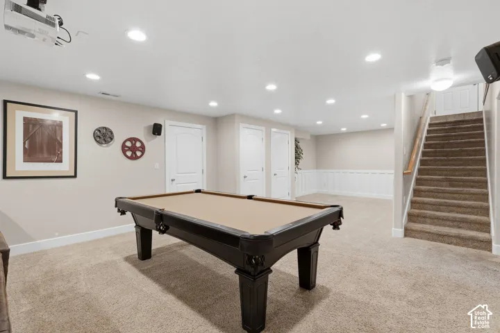 Carpeted flooring, recessed lighting, white paneled wainscoting, and a carpeted staircase with a wood handrail