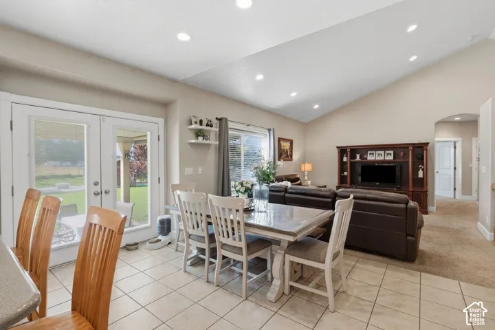 Vaulted ceiling with recessed lighting, tile flooring, glass French doors, and an arched doorway