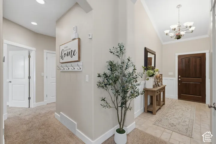 Varnished wood-finish entry door, tiled flooring, vaulted ceiling, and recessed lighting