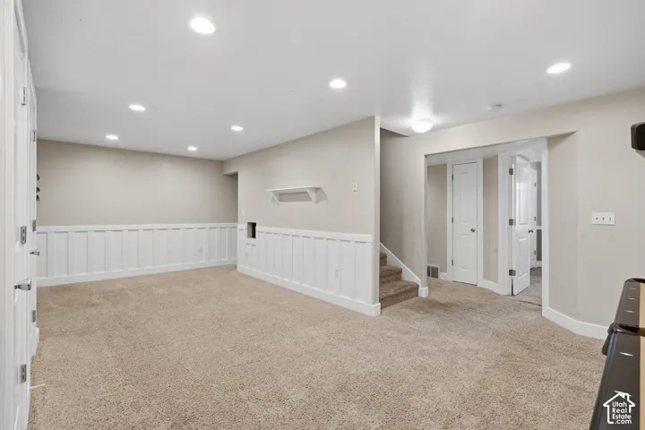 Carpeted flooring, recessed lighting, white wainscoting, and a built-in wall shelf