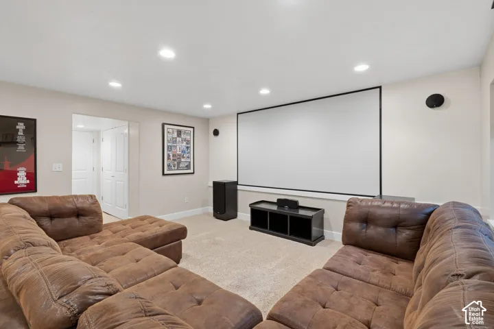 Spacious media room featuring a large projection screen, recessed lighting, and light-colored carpeting
