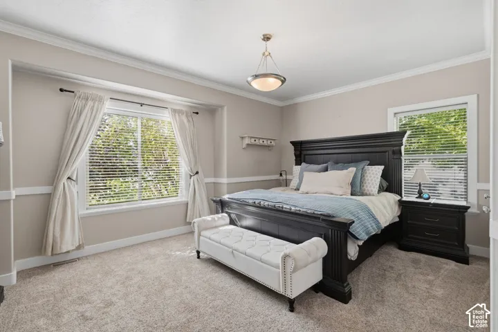 Crown molding accentuating the ceiling line, neutral wall tones, large window with blinds, and recessed wall paneling